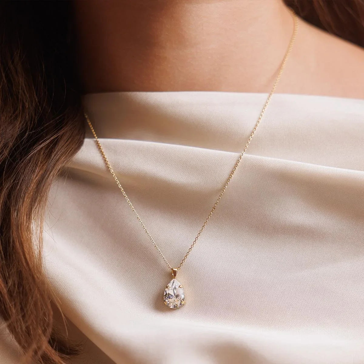 A woman wearing a piece of jewelry consisting of a metal chain and a crystal pendant